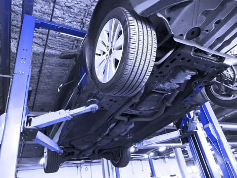 Carolina Collision and Frame Service | Close up of a car's tire as it sits on top of a lift in an auto shop