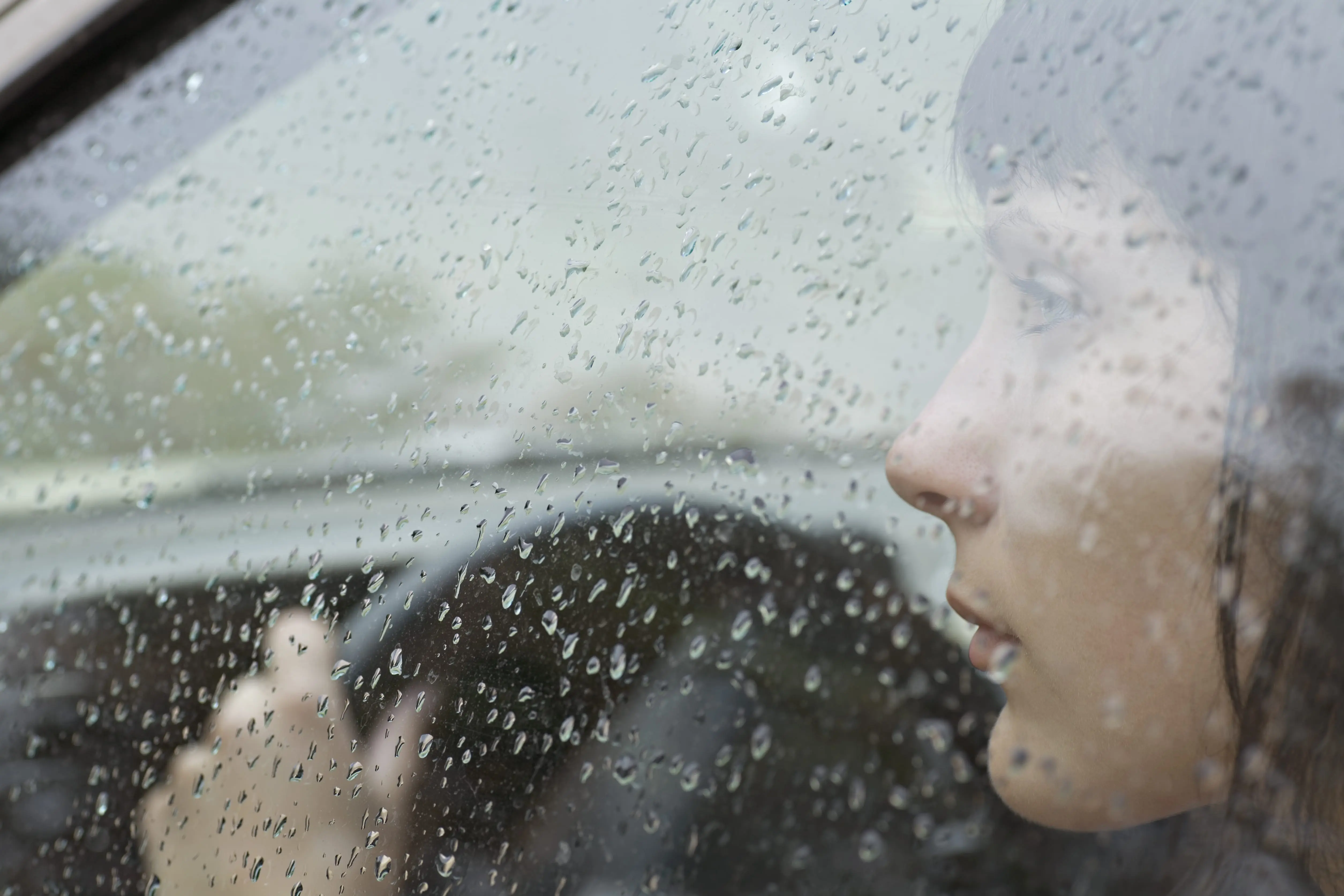 Carolina Collision and Frame Service | Rain on the window of a car being driven by a woman looking concerned