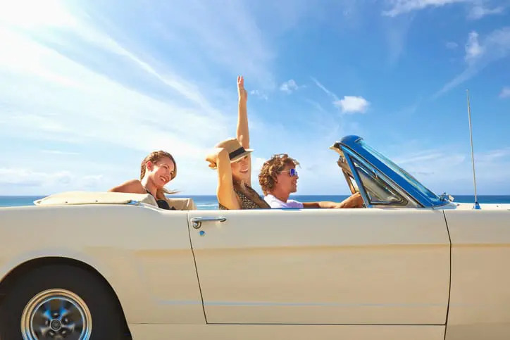 Carolina Collision and Frame Service | Group of friends riding in a beige convertible with a clear blue sky backdrop