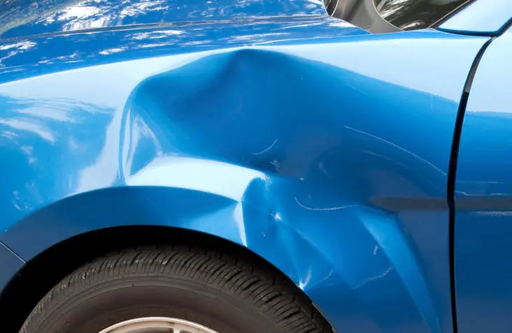 Carolina Collision and Frame Service | Close up of dented panel on a blue car