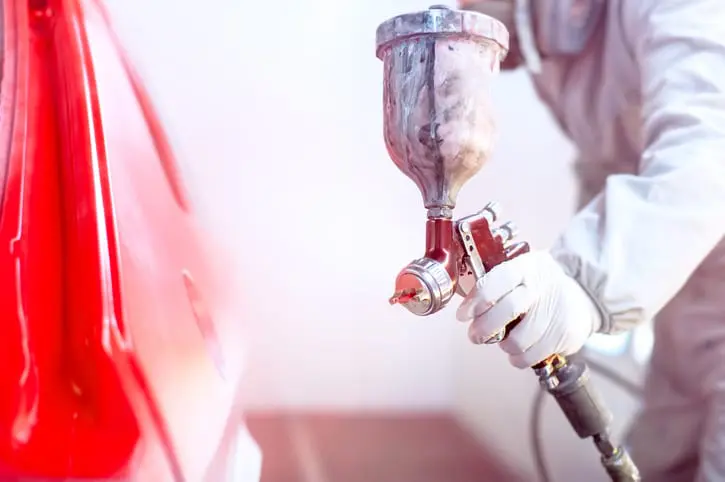 Carolina Collision and Frame Service | Close up of a spray gun spraying red paint on the side of a car