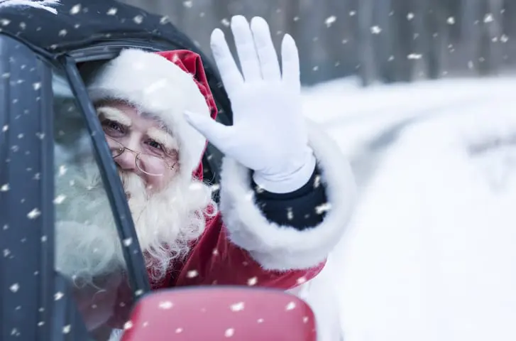 Carolina Collision and Frame Service | Santa Claus wearing white gloves waving outside of the side of a car in the snow
